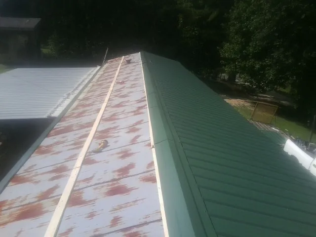 Old rusted panels beside newly installed green metal roofing — Wind Damage Roof Repair by Roofing Brothers in Matagorda