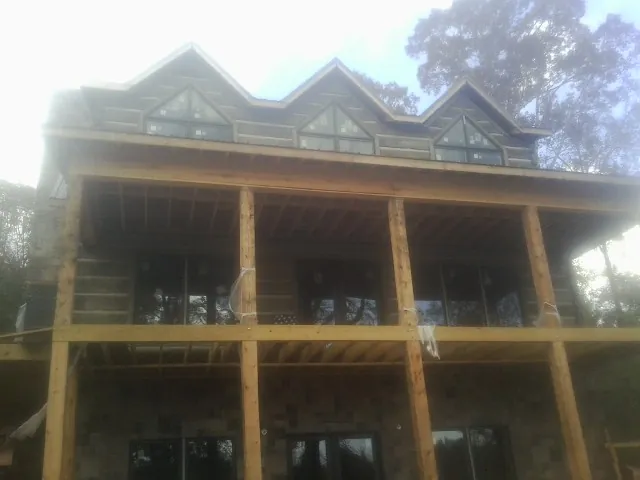 Dormers and porch framing on a large log home under construction — Roof Coating work by our crew in Matagorda