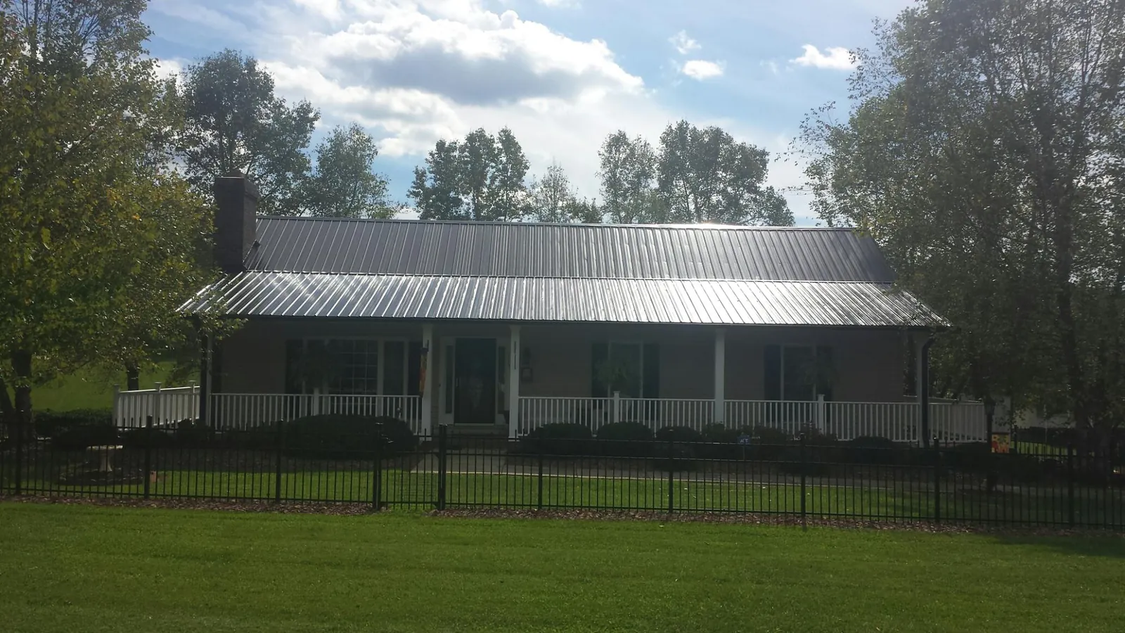 Gray metal roof on a brick ranch with a full width front porch — Gutter Guard Installation work by our crew in Matagorda